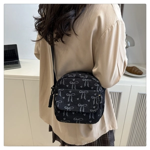 Détail d'un sac bandoulière en velours côtelé noir avec nœuds et cœurs sur un modèle
