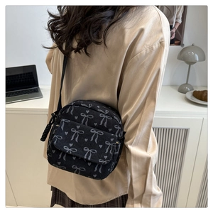 Détail du sac à bandoulière en velours noir avec motifs de nœuds blancs et cœurs