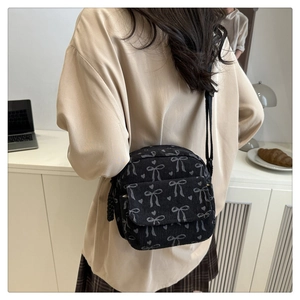 Détail du sac à main en velours noir à motifs de cœurs et nœuds porté à l'épaule