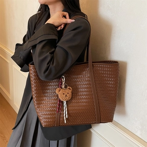 Borsa tote in pelle intrecciata marrone scuro con design minimalista e ciondolo a orsetto