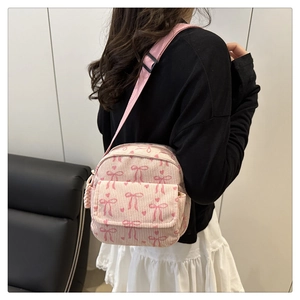 Détail du sac à bandoulière en velours côtelé rose avec motifs de nœuds foncés