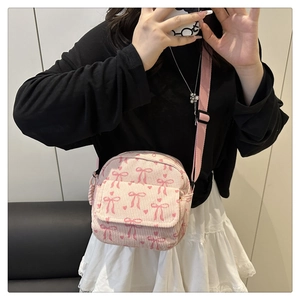 Détail du sac à main en velours côtelé rose avec motifs nœuds et bandoulière réglable