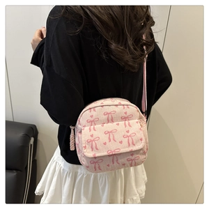 Détail d'un sac bandoulière en velours côtelé rose avec motifs de nœuds et bijoux