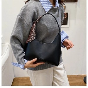 Détail d'un sac demi-lune en similicuir noir avec un foulard en soie sur l'anse