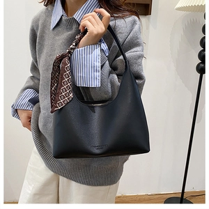 Détail du sac hobo noir avec texture litchi et foulard en soie stylé sur la poignée