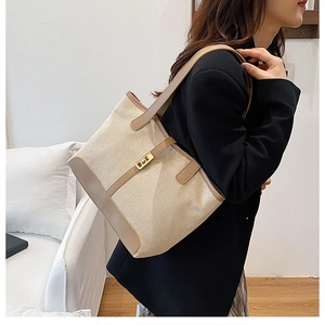 Détail du sac cabas beige avec bordure en cuir marron et fermoir rotatif doré