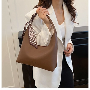 Detail of a dark brown matte leather hobo bag with an elegant patterned silk scarf handle