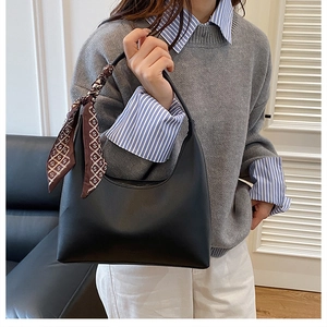 Détail du sac hobo en cuir noir avec un foulard en soie imprimé élégant sur la poignée