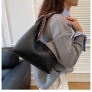 Détail du sac hobo en cuir noir avec foulard en soie vintage sur la bandoulière sur mannequin