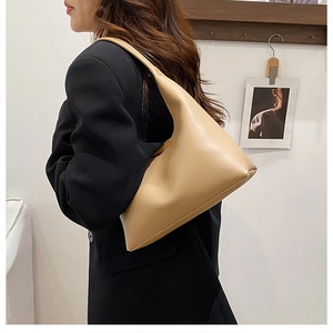 Detail of beige faux leather shoulder bag with printed text and soft matte finish