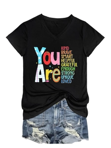 Flat lay of a black V-neck T-shirt with inspirational text and ripped denim shorts