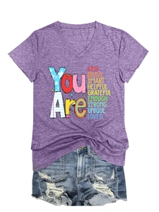 Close-up of purple V-neck t-shirt with rainbow motivational text and denim shorts