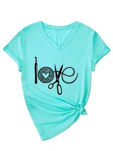 Détail du t-shirt vert menthe à col en V avec motif love, outils de tricot et nœud à l'ourlet