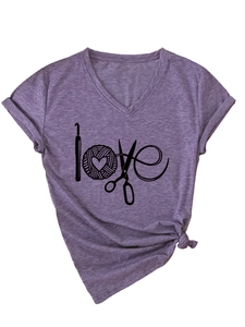 Détail du t-shirt violet à col en V avec le mot love formé par des outils de tricot