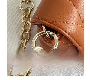 Detail of golden metal strap ring and chain on brown lychee grain leather bag