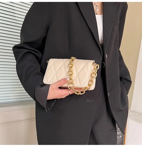 Close-up of quilted cream leather crossbody bag with chunky gold chain strap detail