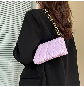Detailed view of lavender quilted leather bag with chunky gold chain strap on model