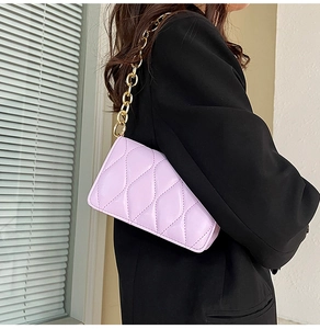 Detail of light purple quilted shoulder bag featuring chunky gold chain and large diamond stitching