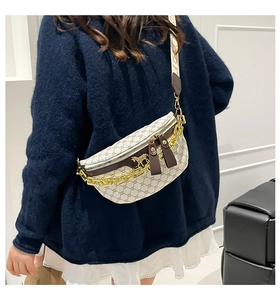Detail of crossbody saddle bag with vintage pattern and decorative gold chain strap