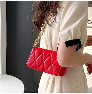 Detail of red quilted crossbody bag with luxury wavy texture and gold chain strap