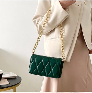 Detail of dark green quilted shoulder bag with chunky gold chain strap and soft texture
