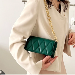 Detail of dark green crossbody bag with wavy stitching and chunky gold chain strap