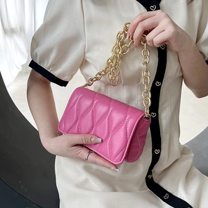 Pink quilted crossbody bag with gold chain handle worn by a model in beige dress