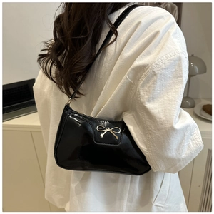 Glossy black patent leather underarm bag with decorative gold metal bow detail