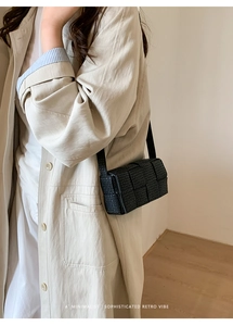 Detail of black woven shoulder bag texture styled with a beige trench coat