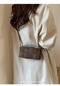 Minimalist woven crossbody bag shown from behind on a model wearing an oversized beige trench coat