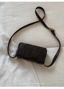 Macro detail of dark brown woven leather texture on a minimalist retro crossbody bag