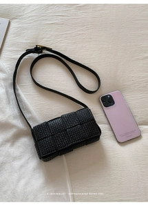 Detail view of woven square bag with gold buckle next to a phone for size scale