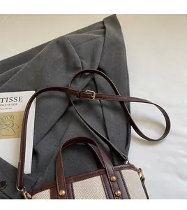 Détail du sac seau en toile avec bordure en cuir marron et bandoulière réglable