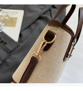 Détail du sac seau en toile avec garniture en cuir marron et finitions métalliques dorées