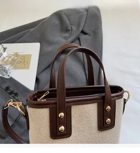 Détail du cabas en toile avec garniture en cuir, rivets dorés et fermeture éclair