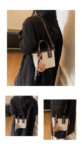 Détail du sac seau bicolore avec bordure en cuir et porte-clés ourson décoratif