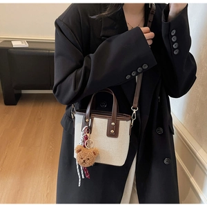 Mini sac seau en toile porté avec breloque ourson et bandoulière en cuir amovible