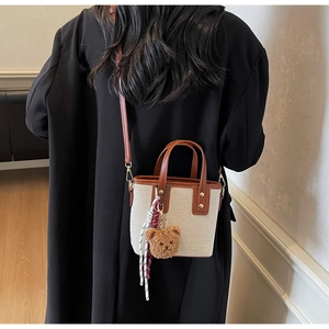 Détail du sac seau en toile avec lanières en PU marron et breloque en forme d'ours en peluche