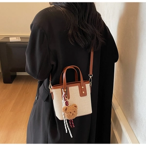 Vue de dos d'un sac seau en toile avec finitions en cuir marron sur un blazer noir