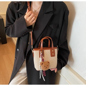 Détail du sac en toile beige avec garniture en cuir marron et breloque ours sur modèle