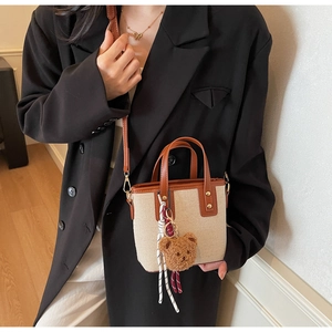 Détail du sac cabas bicolore beige et marron avec bandoulière et breloque ourson