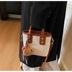 Détail du mini sac cabas en toile avec lanières en cuir et breloque ours en peluche