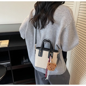 Détail du sac seau en toile avec finitions en cuir noir et breloque ours mignonne