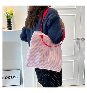 Détail du cabas en toile à rayures roses et blanches avec bandoulières rouges