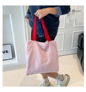 Détail du sac cabas en toile à carreaux roses avec anses rouges dans une scène de vie