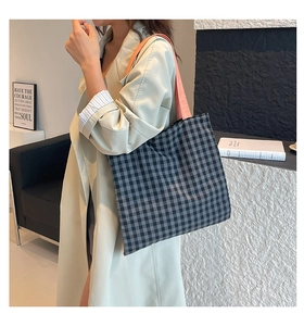 Détail d'un sac cabas à carreaux noir et blanc avec une bandoulière orange corail vif