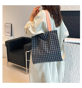 Détail du sac cabas en toile à carreaux avec bandoulière rose porté de côté par un mannequin