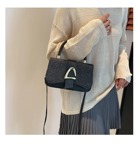 Detail of black glitter crossbody bag with gold D-ring buckle worn with a casual outfit