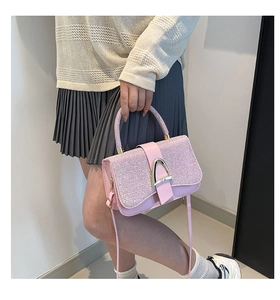 Pink sequin crossbody bag with gold metallic buckle and handle held by a model