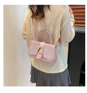 Detail of glitter pink crossbody bag with golden horseshoe buckle on elegant model